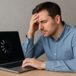 Frustrierter Mann vor langsamem Laptop mit Ladeanzeige