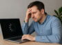 Frustrierter Mann vor langsamem Laptop mit Ladeanzeige