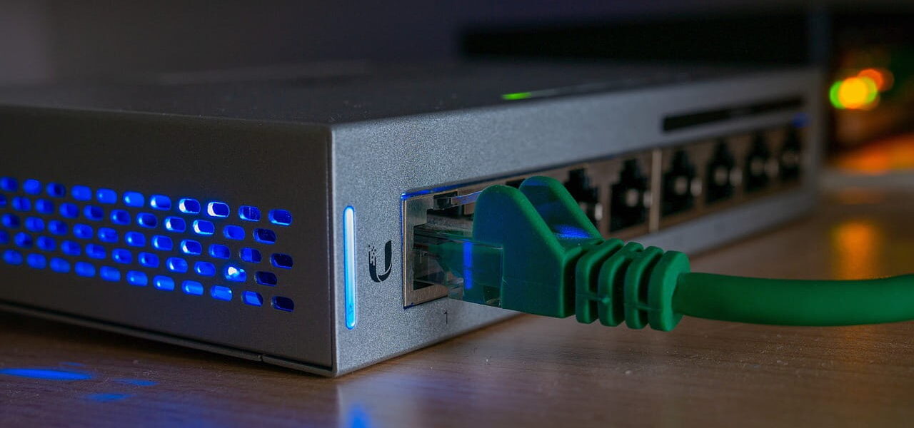 Netzwerk Switch mit eingestecktem LAN-Kabel und aktiven Status-LEDs im Heimnetz