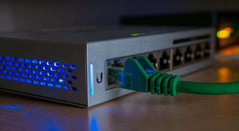 Netzwerk Switch mit eingestecktem LAN-Kabel und aktiven Status-LEDs im Heimnetz